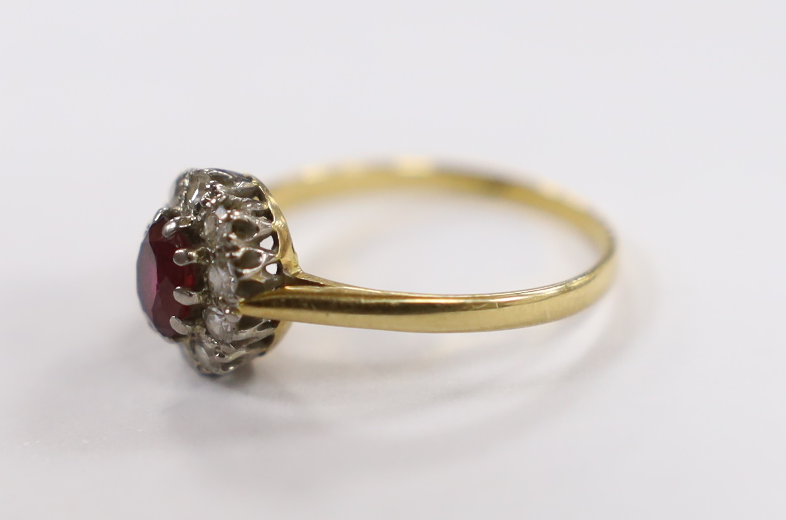 An 18ct, ruby and diamond set oval cluster ring, size N/O, gross weight 2.5 grams.